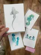 Hand holding a card with a shark illustration among other cards on a wooden surface