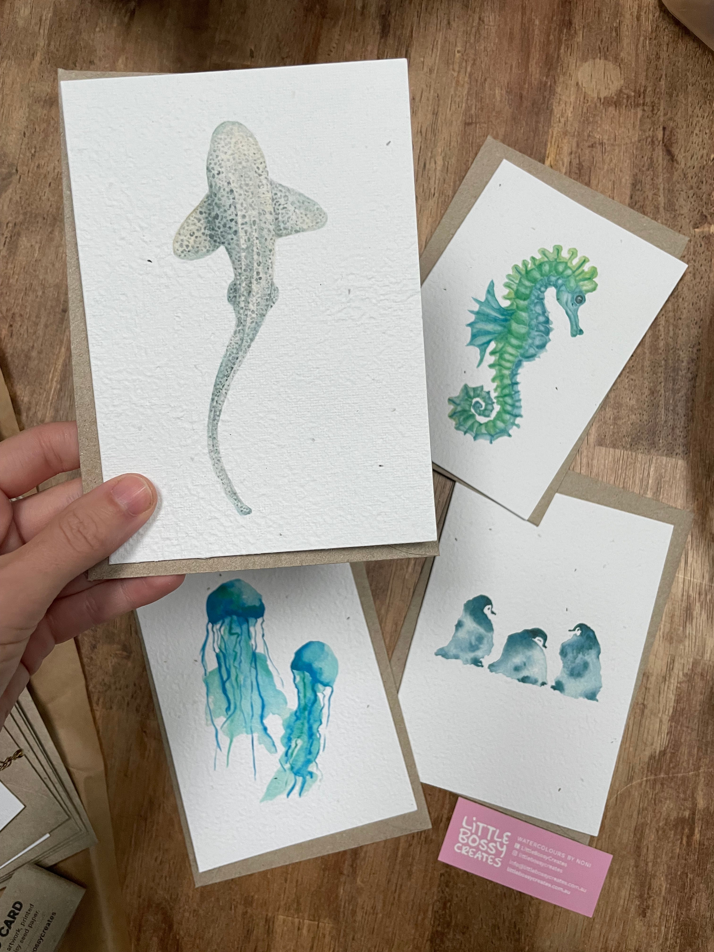 Hand holding a card with a shark illustration among other cards on a wooden surface